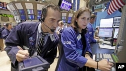 Trader Gregory Rowe and specialist Jennifer Klesaris work on the floor of the New York Stock Exchange, Friday, Aug. 12, 2011