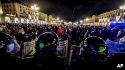 Policías antimotines vigilan a miles de italianos que protestan airados contra las nuevas restricciones.