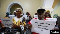 FILE - Grieving parents hold up signs during a news conference, calling for justice for the deaths of children linked to contaminated cough syrups, in Serekunda, Gambia, November 4, 2022.