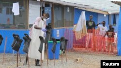 FILE - Boys stand in the "red zone" where they are being treated for Ebola at the Bong County Ebola treatment unit about 200 km east of Monrovia, Liberia, Oct. 28, 2014. 