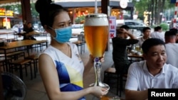 A woman serves beer at a restaurant after the govenment eased nationawide lockdown during the coronavirus disease (COVID-19) outbreak in Hanoi, Vietnam April 29, 2020. 