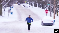 Un hombre corre por una calle cubierta de nieve en Indianápolis, Indiana, el lunes 6 de enero de 2025. AP