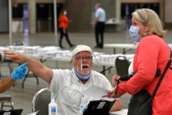 In this Tuesday, June 23, 2020 file photo, poll workers instruct a voter on where to go to fill out their ballot during the Kentucky primary at the Kentucky Exposition Center in Louisville, Ky.