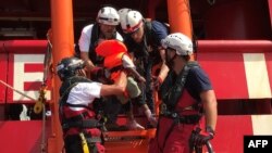 Kru kapal penyelamat 'Ocean Viking' yang dioperasikan LSM Perancis, SOS Mediterranee dan Medecins sans Frontieres (MSF), membantu seorang anak migran Libya naik ke kapal dari perahu karet, 9 Agustus 2019. (Foto: AFP)