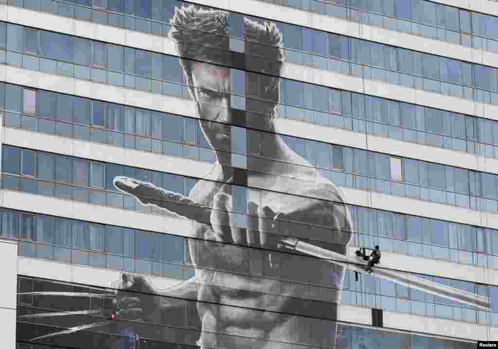 Seorang pekerja memasang sebuah poster raksasa film baru Hugh Jackman berjudul &quot;The Wolverine&quot; di sebuah gedung bertingkat di Bangkok, Thailand.