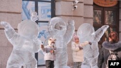 Anak-anak bermain di dekat patung es tiga astronot di Harbin, provinsi Heilongjiang timur laut China, 28 Desember 2021. ( AFP) 