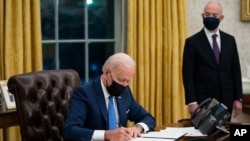 Secretary of Homeland Security Alejandro Mayorkas looks on as President Joe Biden signs an executive order on immigration, in the Oval Office of the White House, Feb. 2, 2021, in Washington.