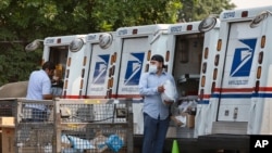 Postal workers load packages in their mail delivery vehicles at the Panorama city post office on Aug. 20, 2020 in the Panorama City section of Los Angeles.