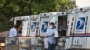 FILE - Postal workers load packages in their mail delivery vehicles at the Panorama city post office on Aug. 20, 2020, in the Panorama City section of Los Angeles.