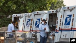 FILE - Postal workers load packages in their mail delivery vehicles at the Panorama city post office on Aug. 20, 2020 in the Panorama City section of Los Angeles.