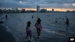 FILE - A woman and a girl walk along the shore to cool off during a heat wave on the coast of Veracruz, Mexico, on June 15, 2024. 