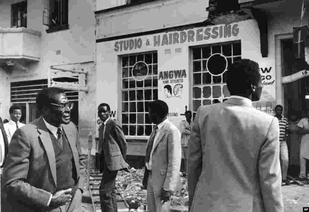 Perdana Menteri Zimbabwe Robert Mugabe berdiri di luar puing-puing gedung markas Dewan Nasional Afrika di pusat Kota Harare, setelah rusak berat akibat serbuan komando Afrika Selatan, 19 Mei 1986. (AP Photo)