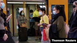 FILE - Sydney commuters wear protective face masks on public transit amid new public health regulations from the state of New South Wales, as the city grapples with an outbreak of COVID-19 June 23, 2021.