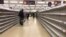 FILE - In this March 19, 2020 file photo, people stand in an aisle of empty shelves in a supermarket in London, amid panic-buying due to the coronavirus outbreak.