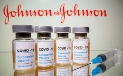 FILE - Vials with a sticker reading, "COVID-19 / Coronavirus vaccine / Injection only" and a medical syringe are seen in front of a displayed Johnson & Johnson logo in this illustration taken Oct. 31, 2020.