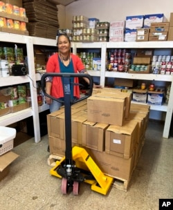 Carey Atchak, the food security director for Bethel Community Services Foundation, stands with a pallet of food for the organization's food pantry in Bethel, Alaska, April 13, 2023.