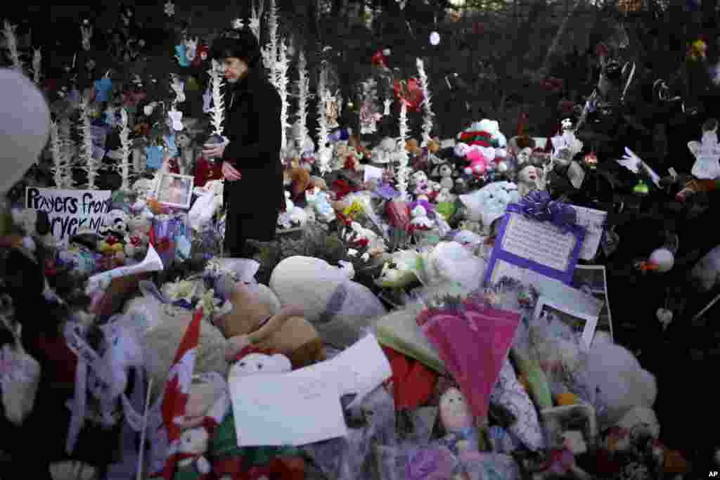 Jeanne Walker walks through an overflowing memorial to the shooting victims, Newtown, Connecticut, December 20, 2012. 