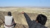 一名居民2024年1月18日展示巴基斯坦西南部俾路支省边境地区的一座山，此前伊朗对那里发动空袭。（法新社照片）
