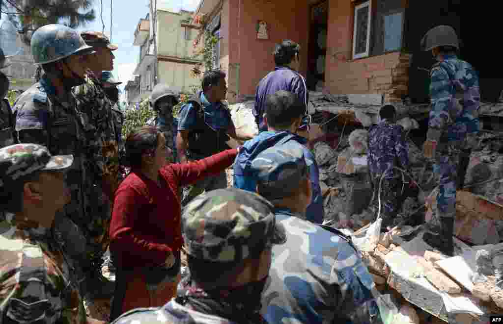 Nepalese resident Sangita Mahat, center, directs police as they retrieve the body of her relative Prasamsah, 14, during rescue efforts in Balaju in Kathmandu.