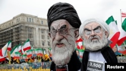 FILE - Protesters yell behind effigies of Iranian President Hassan Rouhani and Supreme Leader Ayatollah Ali Khamenei to rally for government change in Iran during a demonstration in Washington, March 8, 2019.