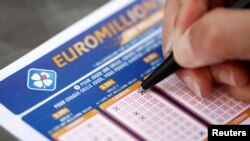 FILE PHOTO: A woman fills out a grid of a lottery ticket for Euro Millions, a lottery game draw, by the French national lottery company Francaise des Jeux (FDJ) in this picture illustration