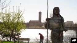 FILE - A man walks past a statue of Sacajawea along the banks of the Missouri River in Great Falls, Montana.