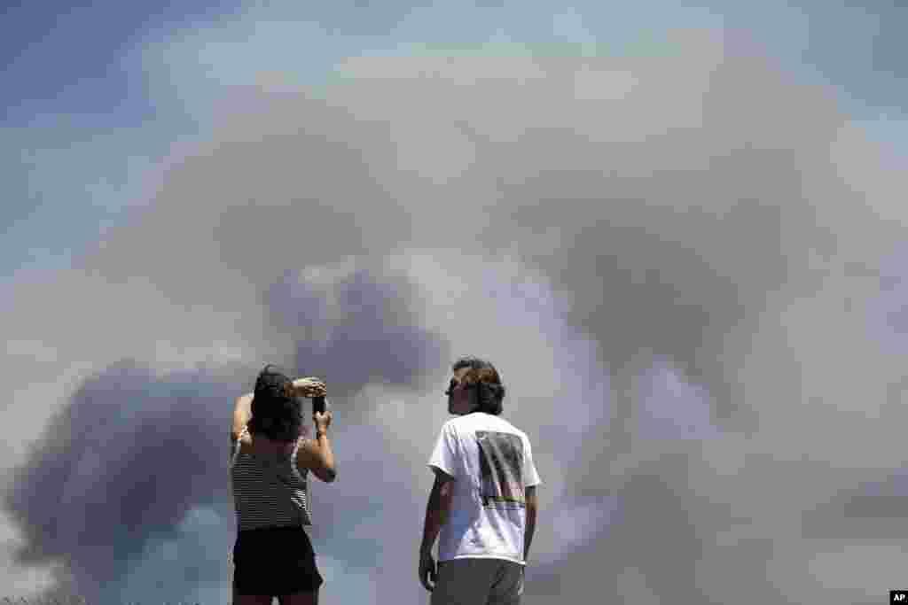 Chase and Brittany Boslet take pictures of smoke from the Las Pulgas fire burning on the Marine Corps Base Camp Pendleton near Oceanside, California, May 16, 2014.