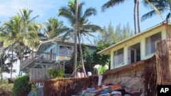 FILE - Sandbags are piled up in front of properties damaged by severe beach erosion in the Rocky Point neighborhood of Oahu's North Shore in Haleiwa, Hawaii, Dec. 31, 2013.