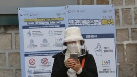 A woman wearing a face mask watches her smartphone in Seoul, South Korea, Saturday, March 21, 2020.