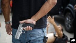 A civil police officer stands guard over a looter shot in the leg by the civil police while looting an electronic store in Vitoria, Espirito Santo state, Brazil, Feb 6, 2017.