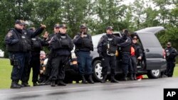 Corrections officers wave to passing motorists who cheered them after the second of two escaped prisoners was apprehended, June 28, 2015, in Constable, New York.