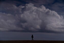 Una mujer pasea por la playa bajo las nubes de lluvia en Seal Beach, California, el miércoles 10 de marzo de 2021.