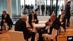 Businessmen check their phones during a break at Argentina's Business and Investment Forum in Buenos Aires, Argentina, Tuesday, Sept. 13, 2016.