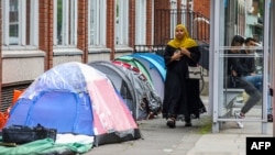 A woman walks past tents at a makeshift refugee camp outside the Irish Governments International Protection Office, in Dublin, Ireland, on June 12, 2023. (Photo by PAUL FAITH / AFP)