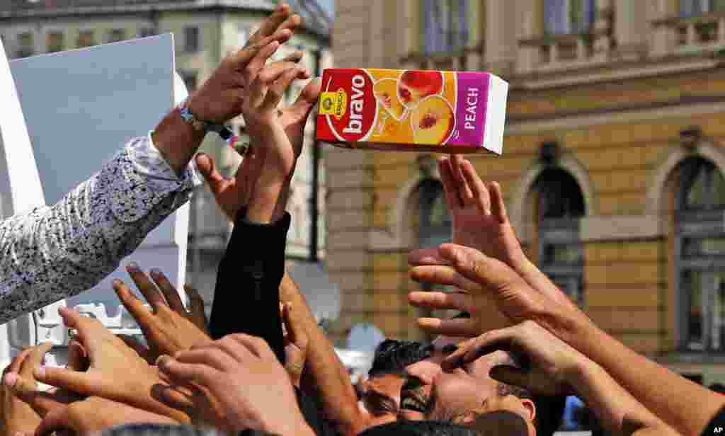 Para migran menerima sumbangan minuman jus di depan stasiun kereta api di Budapest, Hungaria (3/9). Lebih dari 150.000 migran telah mencapai Hungaria tahun ini, sebagian besar melalui perbatasan selatan dengan Serbia. Banyak yang mencari suaka, namun segera mencoba pergi ke negara-negara Uni Eropa yang lebih kaya. (AP/Frank Augstein)