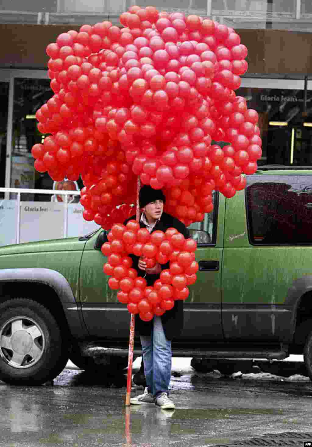 Một thiếu niên bán những bong bóng màu đỏ hình trái tim vào Ngày Valentine tại Ankara, Thổ Nhĩ Kỳ, ngày 14 tháng 2 năm 2012. (AP)