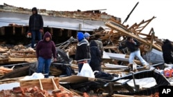 A family digs through the remains of their apartment in Mayfield, Ky., Dec. 11, 2021. 