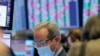 FILE - A trader wears a protective mask as he works on the floor of the New York Stock Exchange (NYSE), in New York City, March 20, 2020.