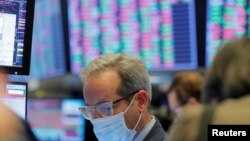 FILE - A trader wears a protective mask as he works on the floor of the New York Stock Exchange (NYSE), in New York City, March 20, 2020.