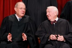 Associate Justices Anthony Kennedy, left, and John Paul Stevens talk to each other as they sit for a new group photograph with other Supreme Court judges, Sept. 29, 2009, at the Supreme Court in Washington.