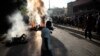 Los transeúntes se reúnen alrededor de los cuerpos de presuntos pandilleros que fueron incendiados por una turba después de que la policía los detuviera mientras viajaban en un vehículo en el área de Canape Vert de Puerto Príncipe, Haití, el lunes 24 de abril de 2023.