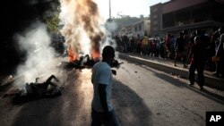 Los transeúntes se reúnen alrededor de los cuerpos de presuntos pandilleros que fueron incendiados por una turba después de que la policía los detuviera mientras viajaban en un vehículo en el área de Canape Vert de Puerto Príncipe, Haití, el lunes 24 de abril de 2023.