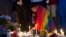 An unidentified man, wrapped in a rainbow flag, lights a candle during a vigil in Washington, June 13, 2016.