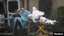 Medics transport a patient through heavy rain into an ambulance at Life Care Center of Kirkland, the long-term care facility linked to several confirmed coronavirus cases in the state, in Kirkland, Wash., March 7, 2020. 