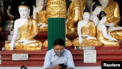 FILE - A man wears a face mask as he uses his phone at Shwedagon Pagoda in Yangon, Myanmar, Jan. 31, 2020.