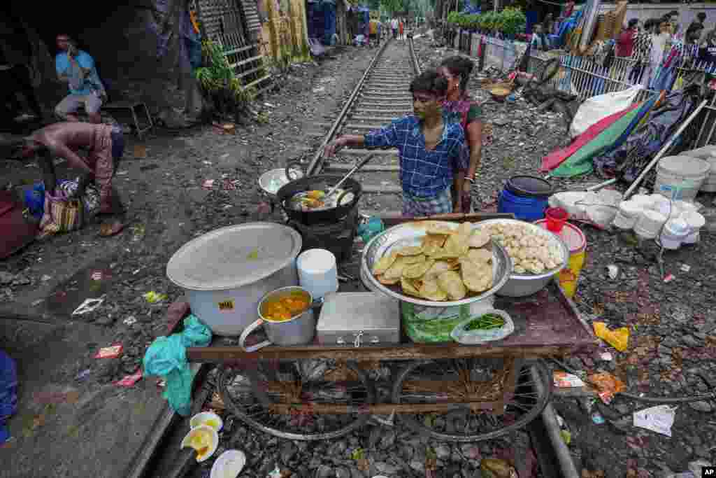 A vendor prepares breakfast on his mobile cart place on a railway track on which train services are suspended temporarily due to festival rush in Kolkata, India.