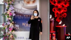 Seorang pegawai toko mengenakan masker di depan pusat perbelanjaan yang sebagian besar tampak sepi di Beijing, China, Sabtu, 7 Maret 2020. (Foto: AP)