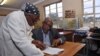 South African musician, Sipho 'Hotstix' Mabuse (R), 60, talks with a classmate as he attends class in a school in Soweto, April 25, 2012.