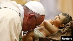 El papa Francisco besa al niño Jesús durante la misa de la Epifanía.