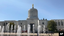 FILE - Children play in fountains at the Oregon State Capitol in Salem, June 29, 2019.